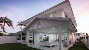 A modern two-story house with a covered patio, a kitchen with a dining area, and a small outdoor seating space.