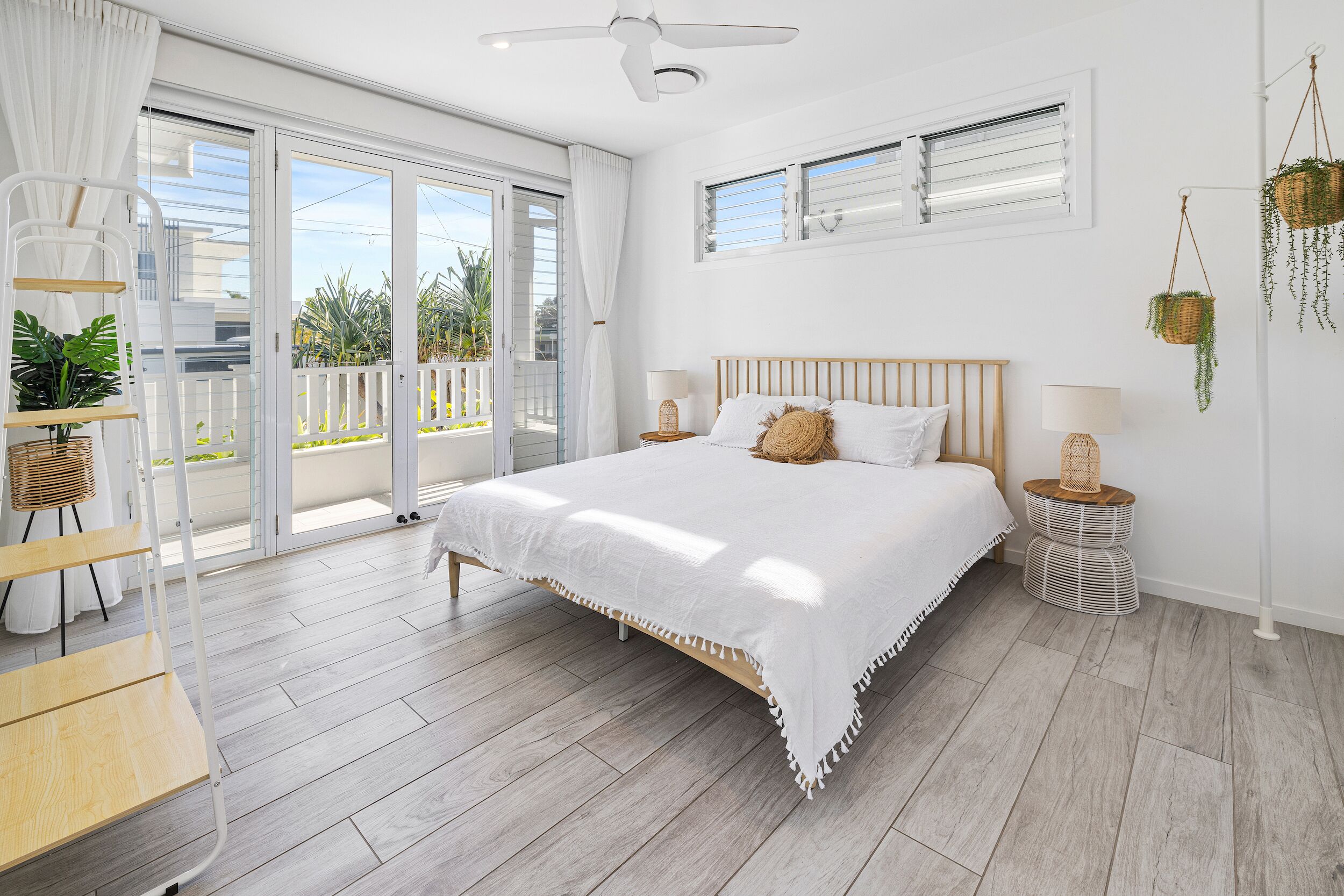 A bedroom with a large bed, a ceiling fan, and a view of the outdoors through a sliding glass door.