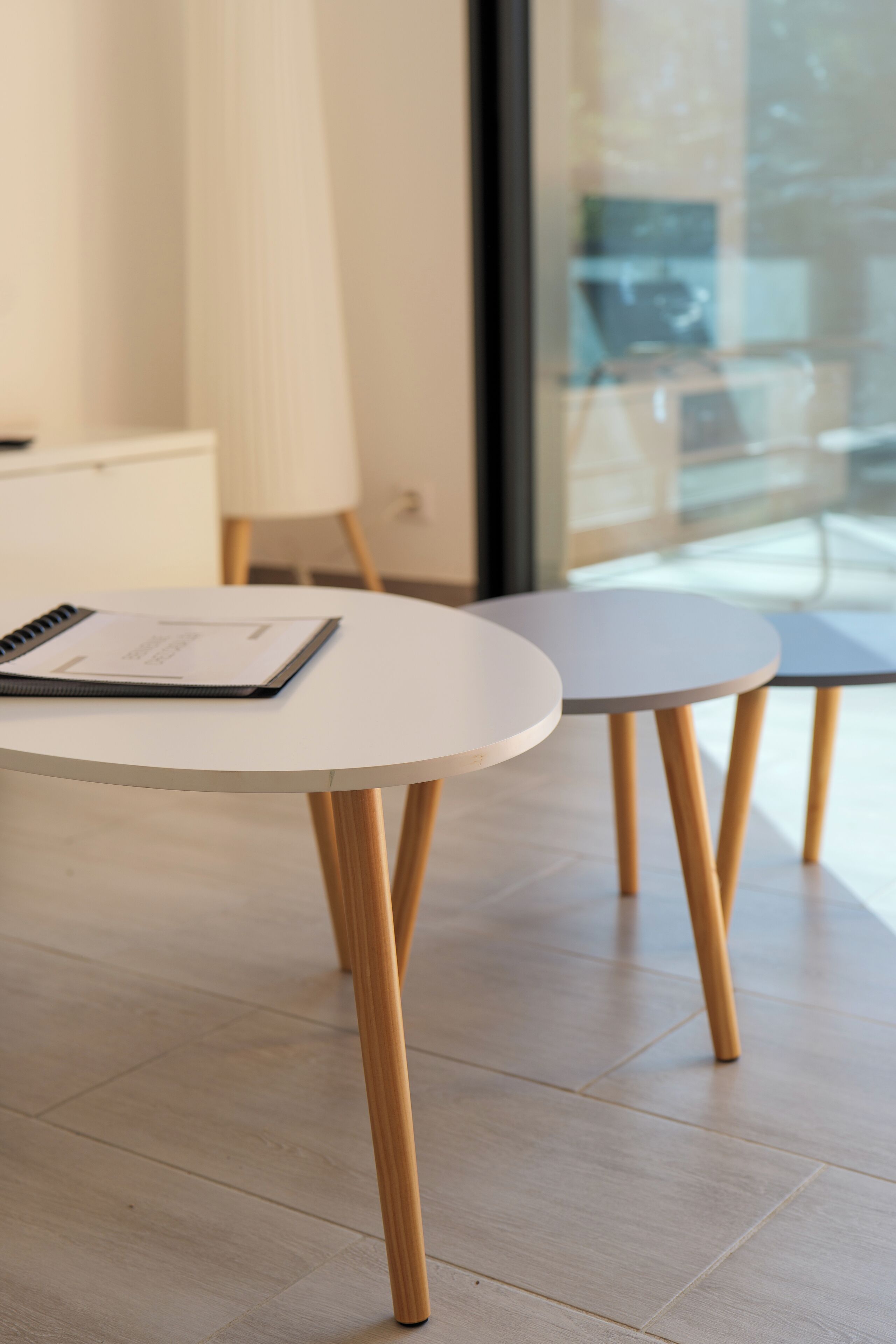 Een moderne kamer met een ronde witte tafel en een kleinere tafel met houten poten.