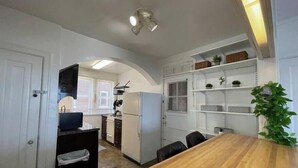A compact kitchen with a dining area, white walls, and a wooden table.
