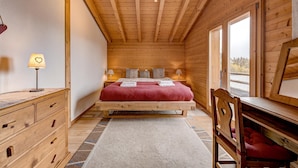 Une chambre dans une cabane en bois, avec un lit, des lampes de chevet, une commode et une chaise.