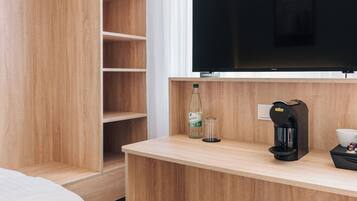 Habitació d'hotel moderna amb escriptori de fusta, televisió de pantalla plana, cafetera i llit.