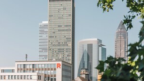Un paisaje urbano con modernos rascacielos, incluyendo un edificio destacado con un letrero 'R'.