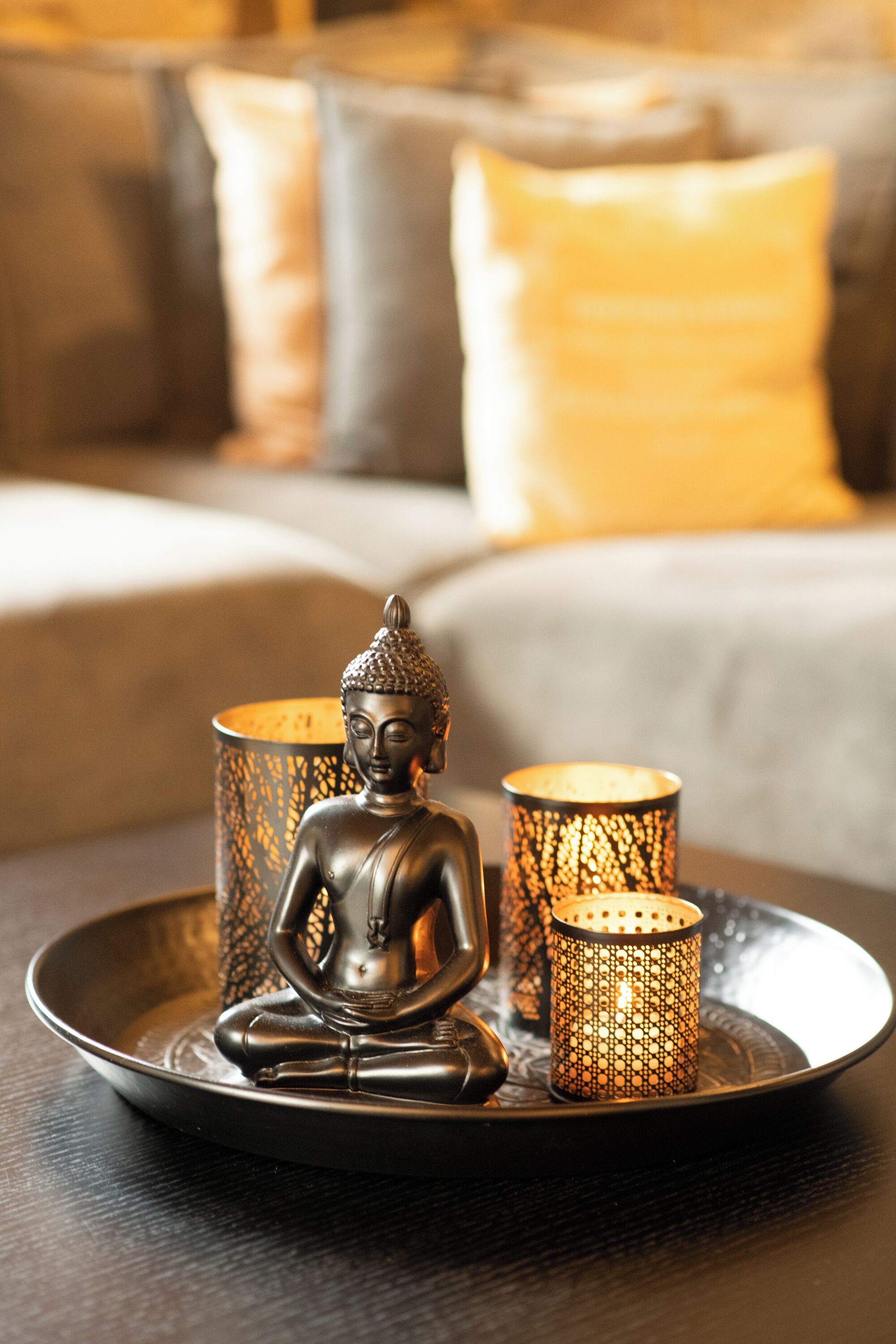 Una statua di Buddha su un vassoio con due candelabri.
