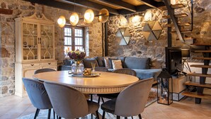 Un comedor rústico con una mesa redonda, sillas tapizadas de gris y un aparador blanco con puertas de cristal.