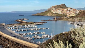 A coastal town with a historic fort, a marina with boats, and a road leading to the town. - Vacation House with panoramic terrace (Castelsardo)