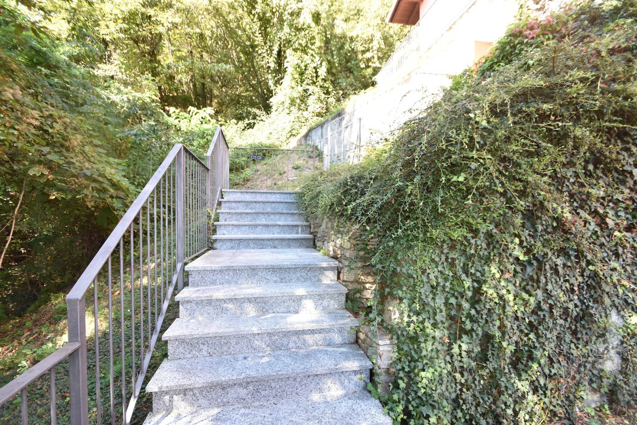 Uma escadaria de pedra com grades de metal serpenteia por uma colina, cercada por vegetação densa.