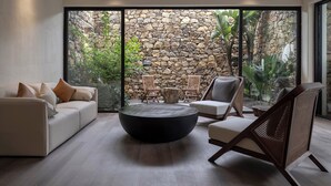 A modern living room with a stone wall, a sofa, two chairs, and a round coffee table. - qingyuansanhedaoli (Qingyuan)