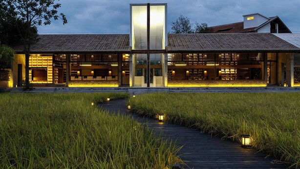 A modern building with a glass facade, wooden deck, and a pathway through a grassy area. - qingyuansanhedaoli (Qingyuan)