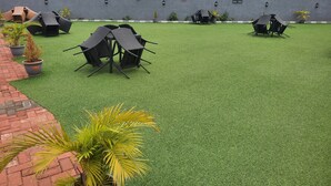 Eine Dachterrasse mit Kunstgrasanlage, Gartenmöbeln und Topfpflanzen.