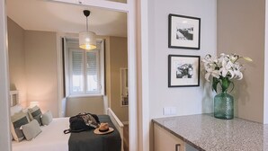 A compact hotel room with a bed, a small kitchenette, and a dining area.