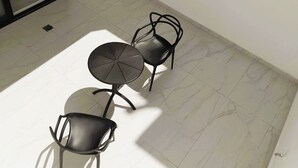 A small, sunlit room with a tiled floor, a round table, and two chairs. - V Luxury Apartments Naxos (Naxos)