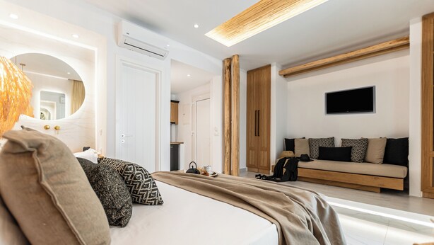 A modern hotel room with a large bed, a TV mounted on the wall, and a wooden accent wall. - V Luxury Apartments Naxos (Naxos)