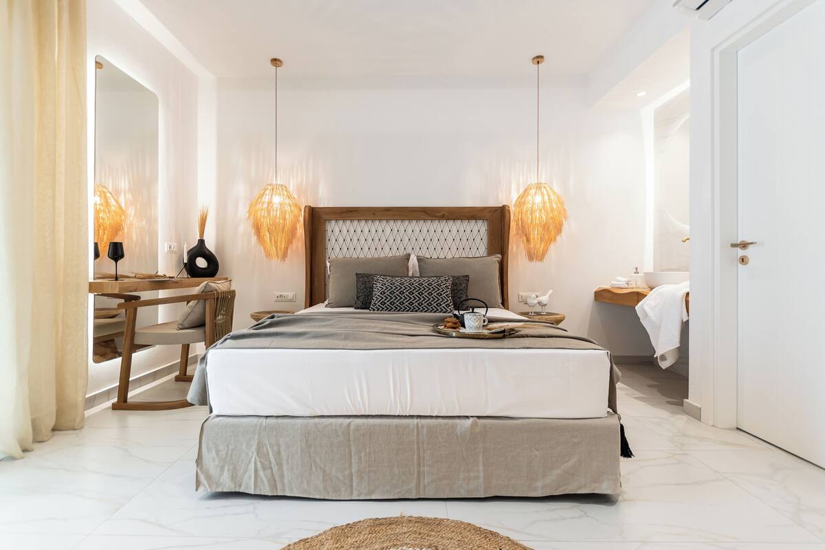 Un dormitorio moderno con una cama grande, mesitas de noche, un escritorio y un espejo.