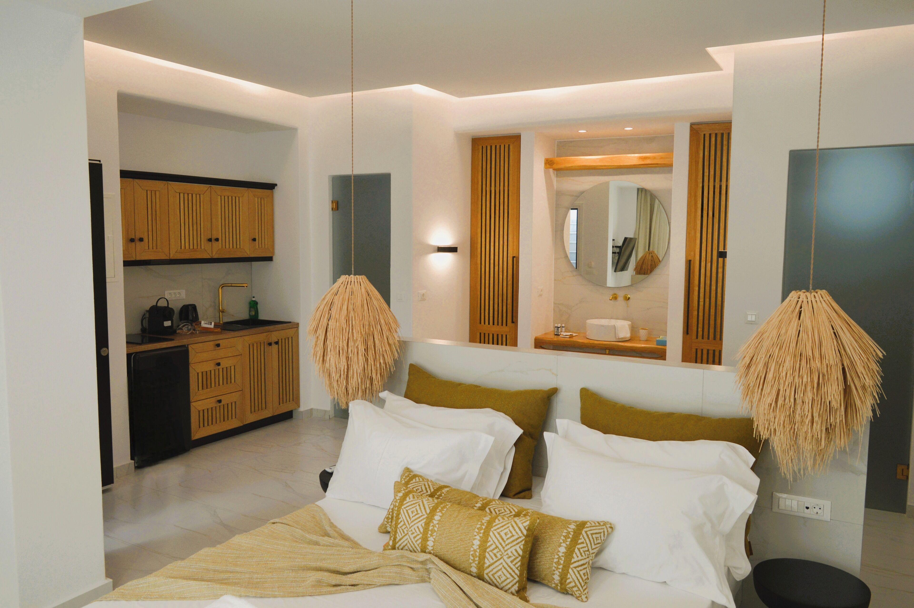 Une chambre à coucher moderne avec un lit, des lampes de chevet et une vue sur la cuisine.