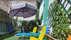 Un espace piscine avec des chaises longues et un parasol.