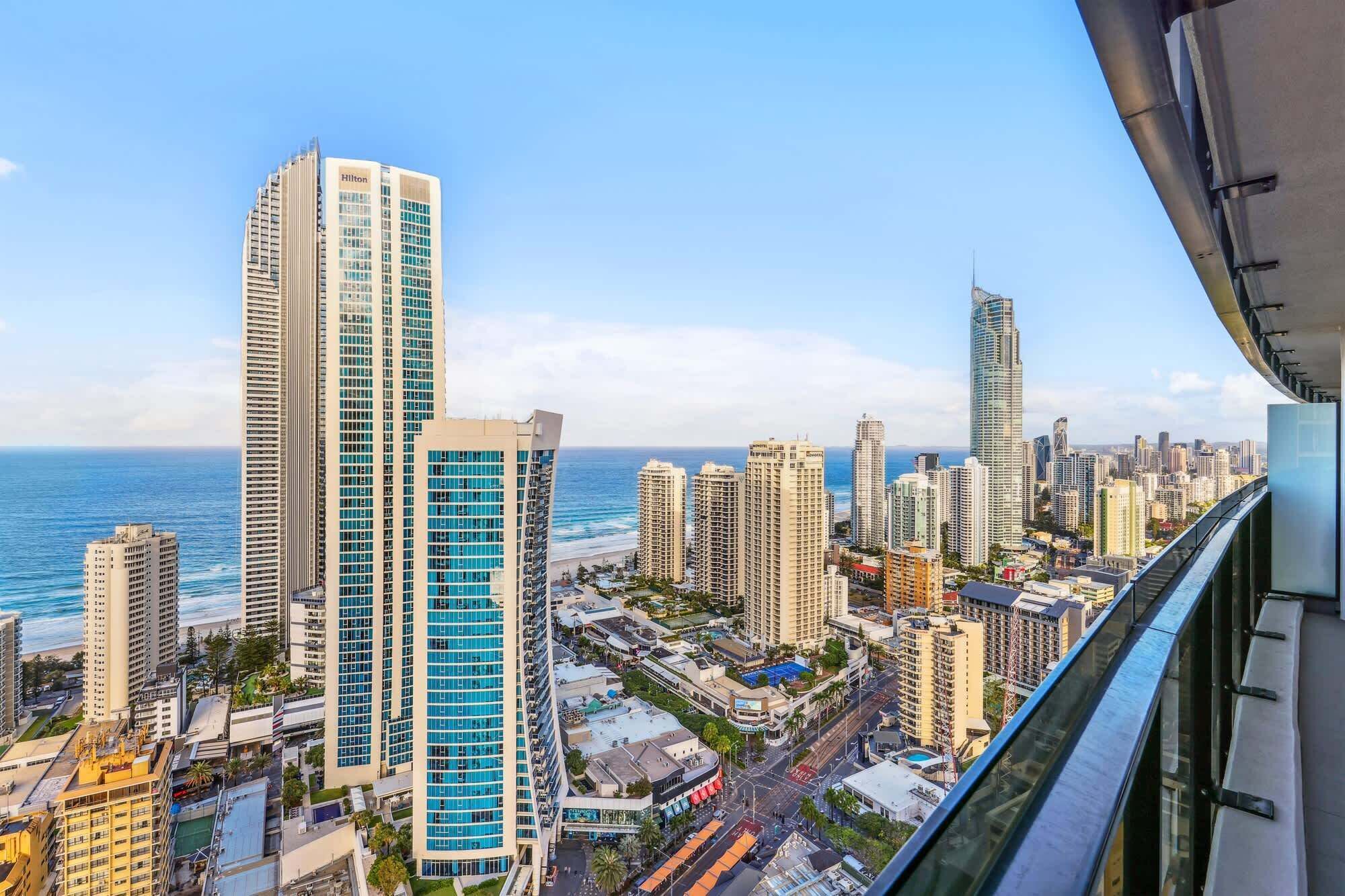 A high-rise hotel with multiple floors, a view of the ocean, and a cityscape in the background.