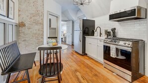 A kitchen with a modern stove, white cabinets, and a brick wall. - Noble Summit BBQ & Fire Pit  & Scenic Views (Colorado Springs)