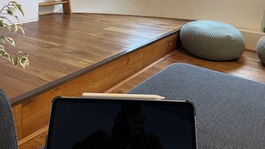 A room with a wooden floor, a ladder, two windows, and a plant.