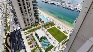 A high-rise building with a marina and a pool in the foreground. - Marina Vista Emaar Beachfront Apartments (Dubai)