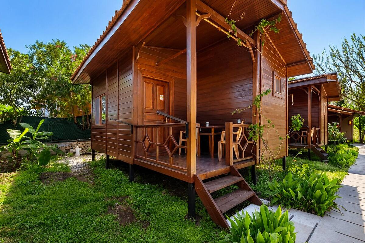 Eine Holzhütte mit Veranda, Sitzgelegenheiten im Freien und einem Garten.