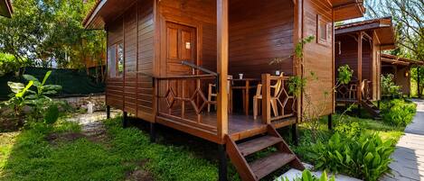 A wooden cabin with a porch, outdoor seating, and a garden.
