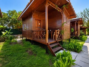 Uma cabana de madeira com varanda, área de estar ao ar livre e jardim.