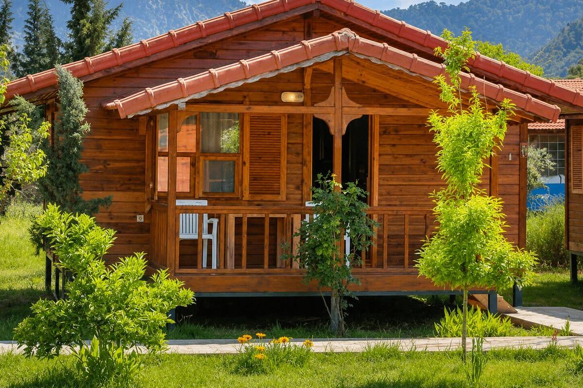 Eine Holzhütte mit Veranda, umgeben von Grün und Bergen.