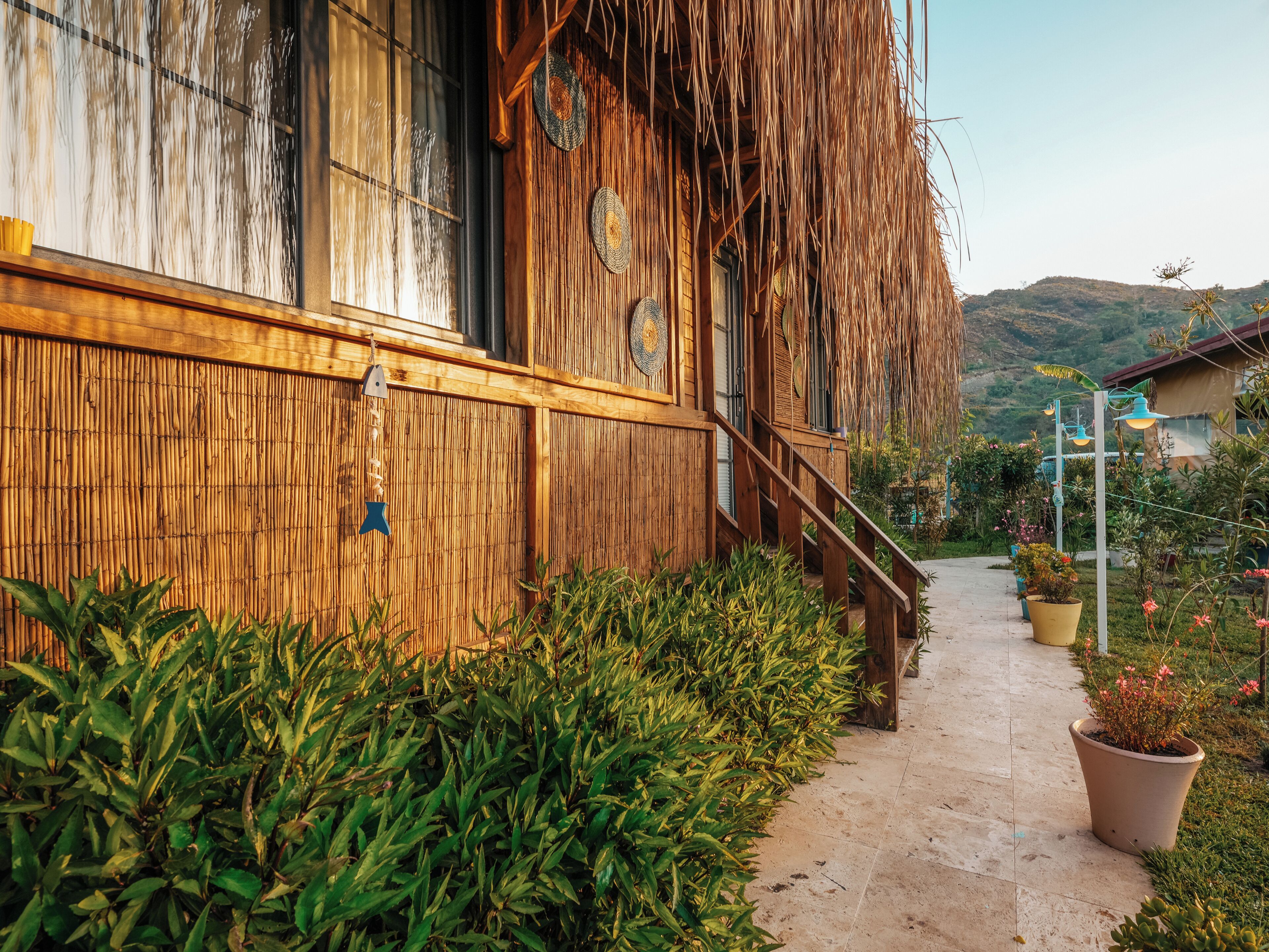 A wooden building with a bamboo wall, a staircase, and potted plants.
