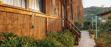 A wooden building with a bamboo wall, a staircase, and potted plants.