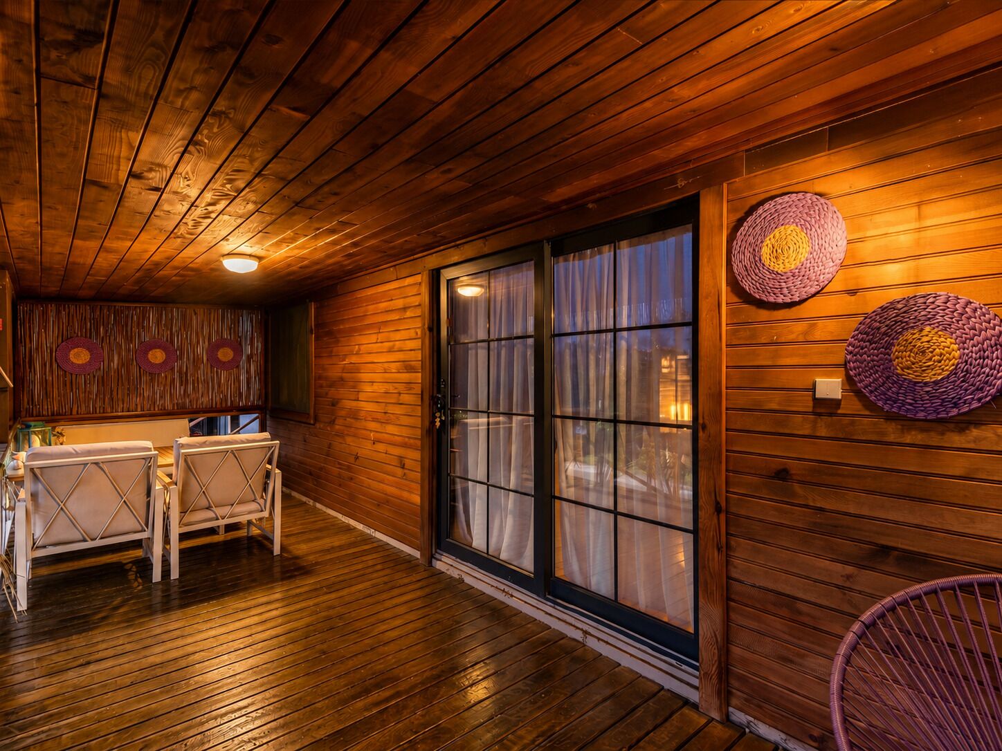A wooden interior with a dining area, large windows, and woven wall decor.