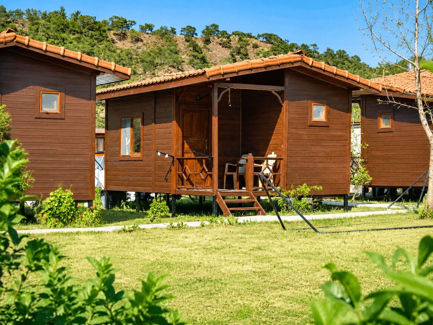 A wooden cabin with a porch, a ladder, and a small deck.