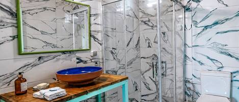 Ein Badezimmer mit Marmor-Spritzschutz, einem Holzbadezimmerschrank, einer Glasdusche und einer Toilette.