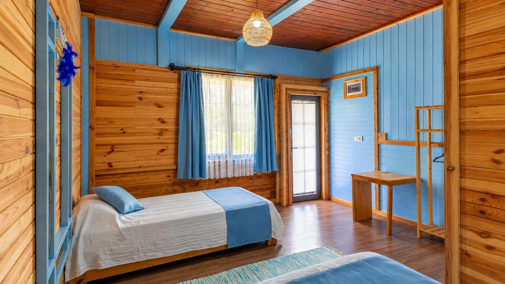 Una habitación con una cama, una mesita y una puerta que da al exterior.