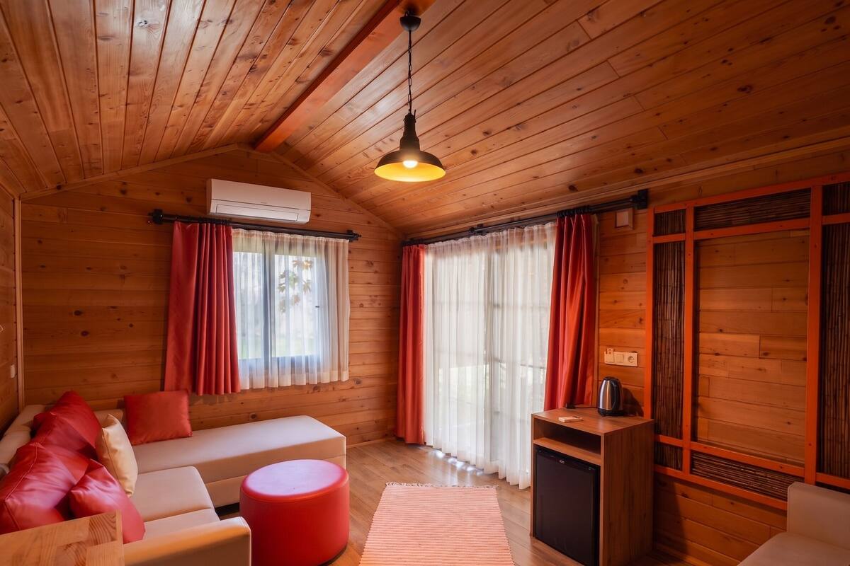 Ein Holzblockhaus-Interieur mit einer Couch, einem Hocker und einem kleinen Tisch mit einem Wasserkocher.