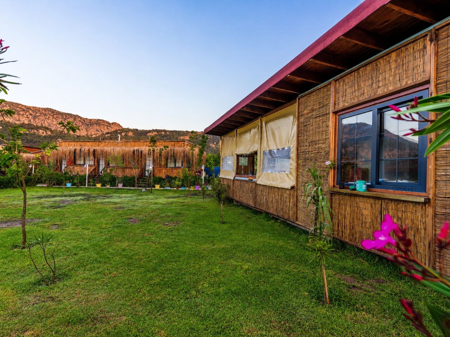 Un edificio con techo de paja, un espacio al aire libre cubierto y un patio con césped.