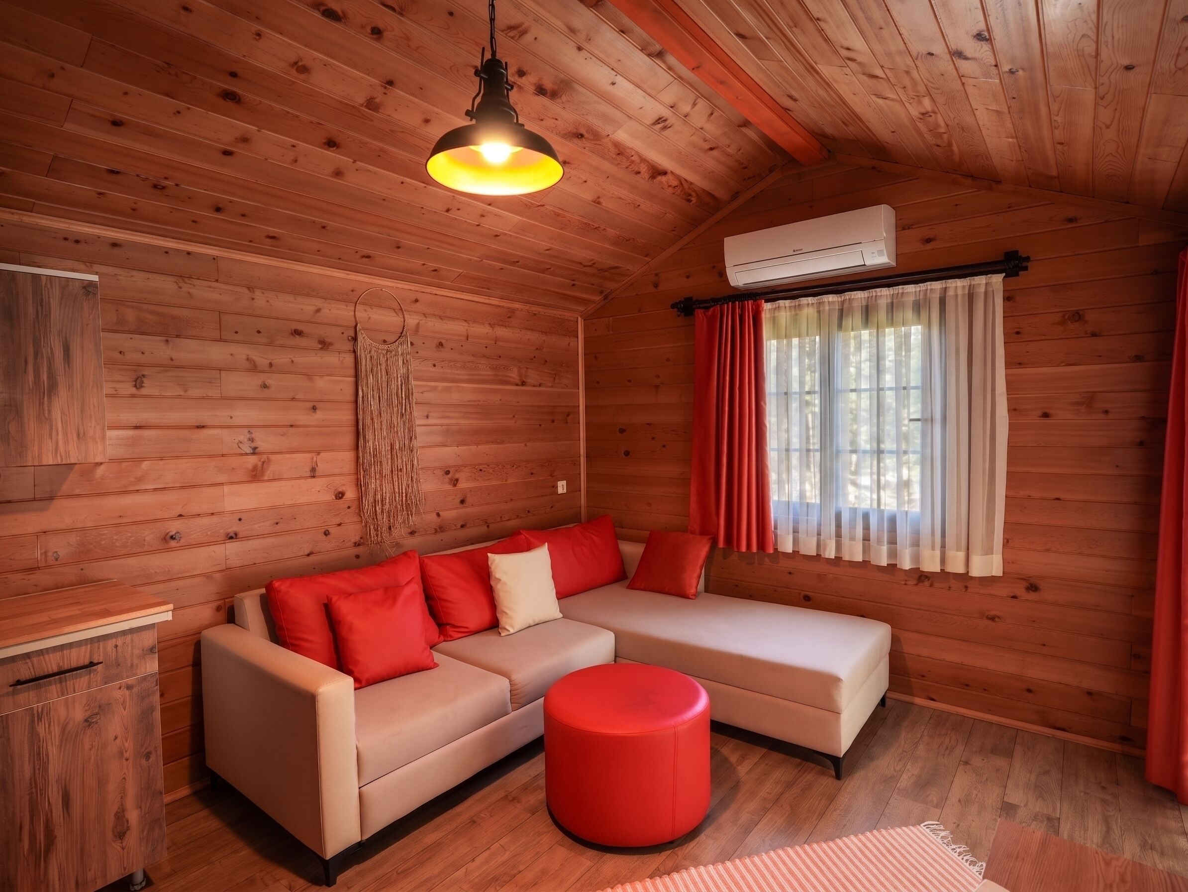 Ein Holzblockhaus-Interieur mit Sofa, Hocker und einer Pendelleuchte.