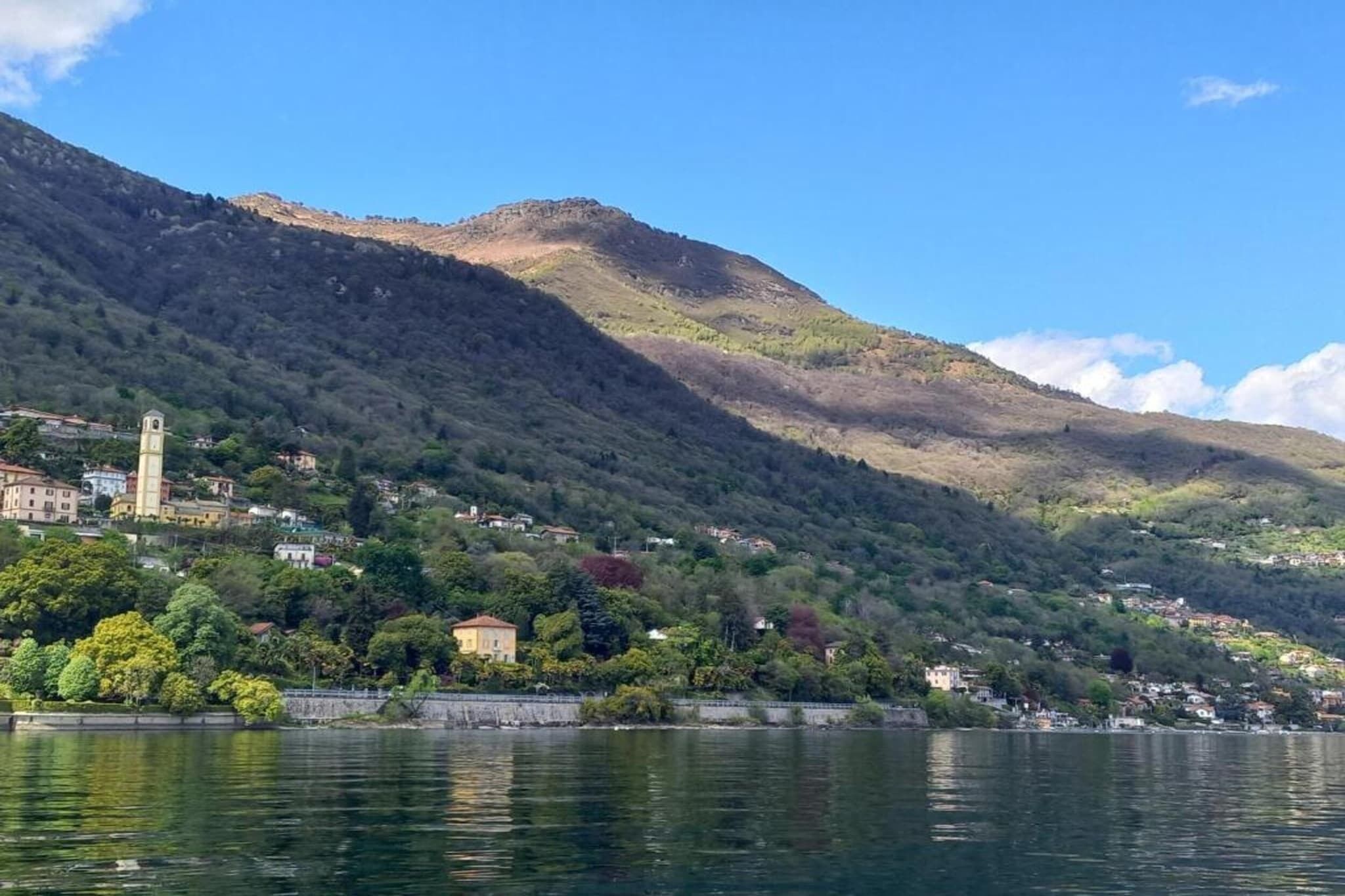 Une ville située au bord d’un lac, caractérisée par une tour imposante, de douces collines verdoyantes et une étendue d’eau paisible.