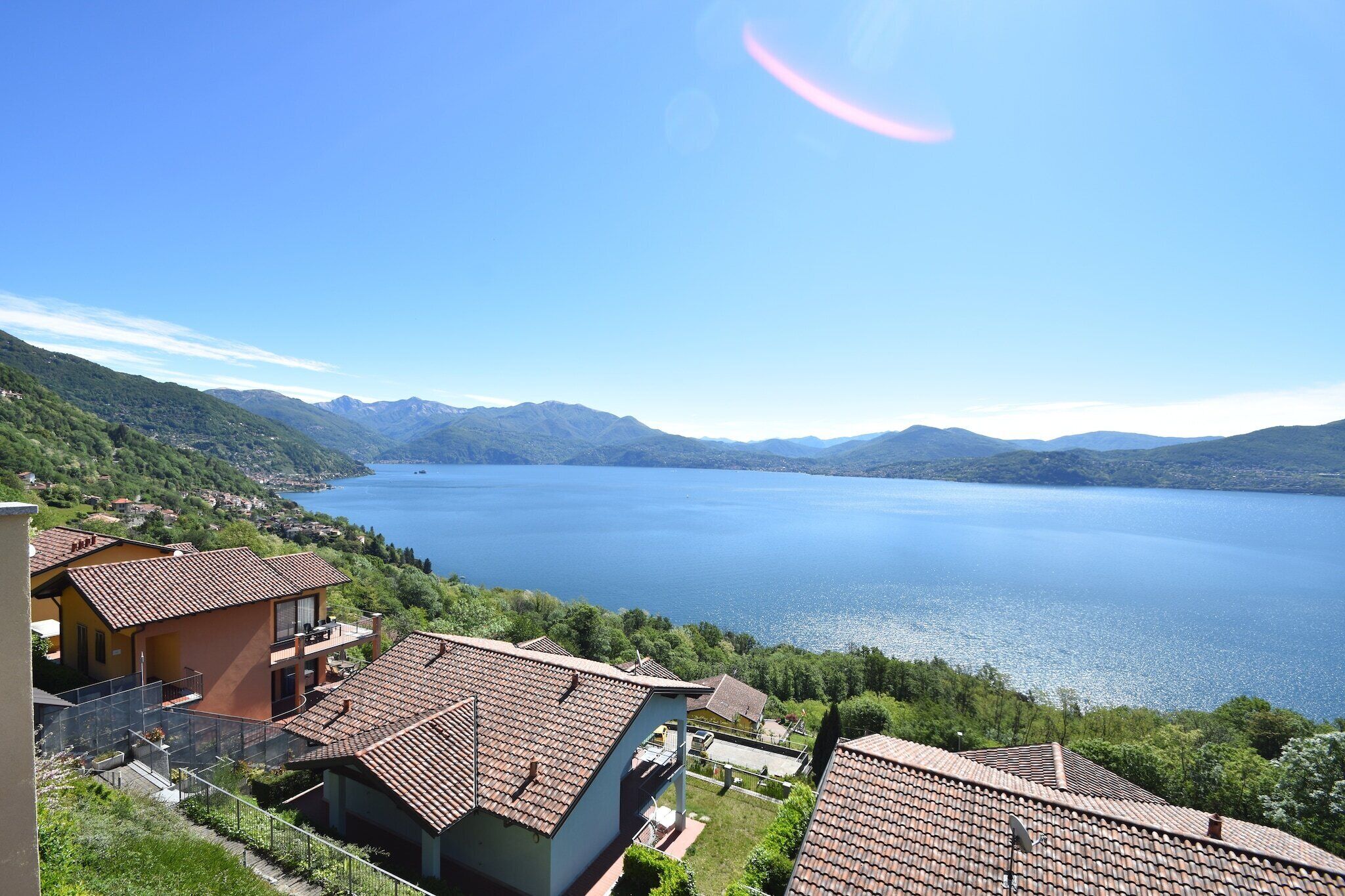 A residential area with houses, a lake, and mountains in the background.