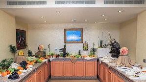 A buffet setup with a variety of fruits and vegetables, a central decorative piece, and a painting on the wall. - Carmen International Hotel (Venus)
