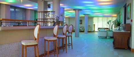 A hotel lobby with a bar area, seating, and a reception desk.