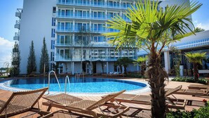 A hotel with a swimming pool, lounge chairs, and palm trees. - Carmen International Hotel (Venus)