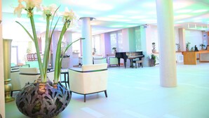 A spacious lobby with a piano, seating areas, and a large decorative vase with flowers. - Carmen International Hotel (Venus)