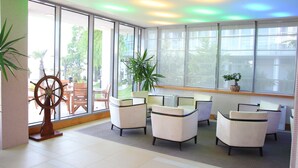 A seating area with white chairs and a ship's wheel decoration. - Carmen International Hotel (Venus)