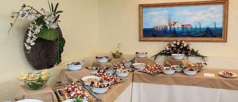 A buffet table with various dishes and a painting of a coastal scene.