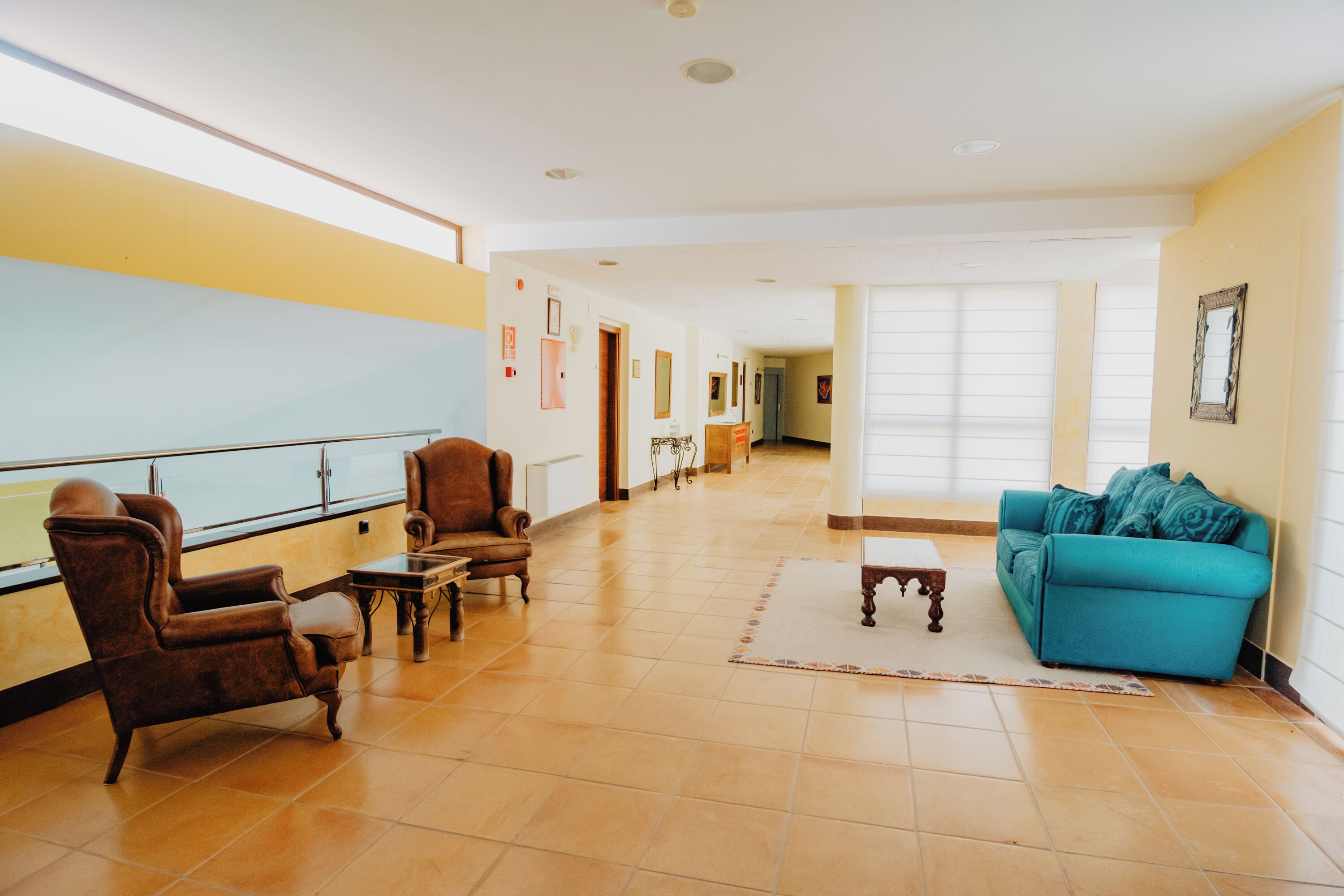 Un vestíbulo espacioso con un sofá azul, sillones de cuero marrón y una mesa de centro de madera.