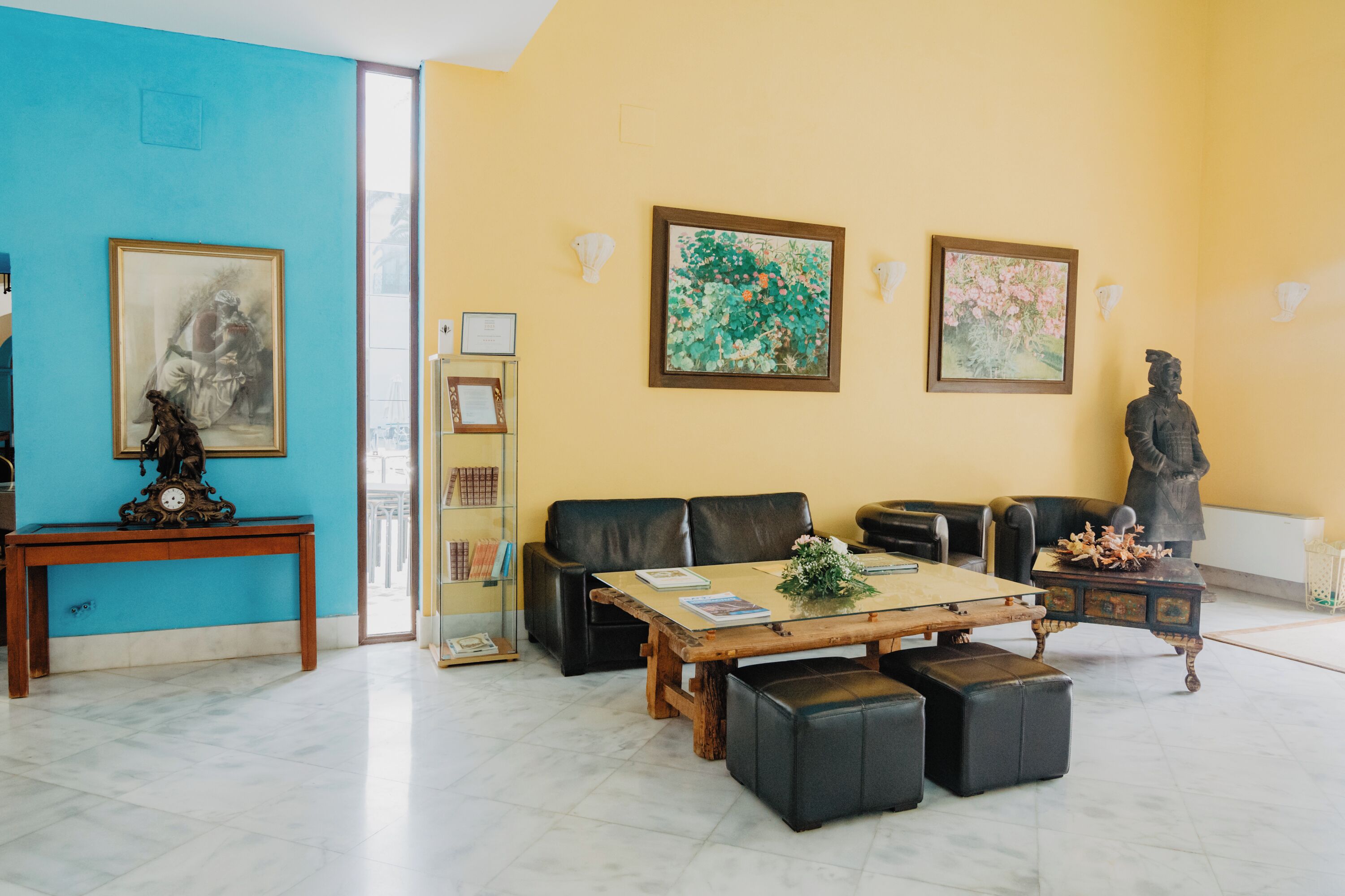 Ein Wohnzimmer mit blauer Wand, einem Holztisch, Ledersofas und einer Statue.