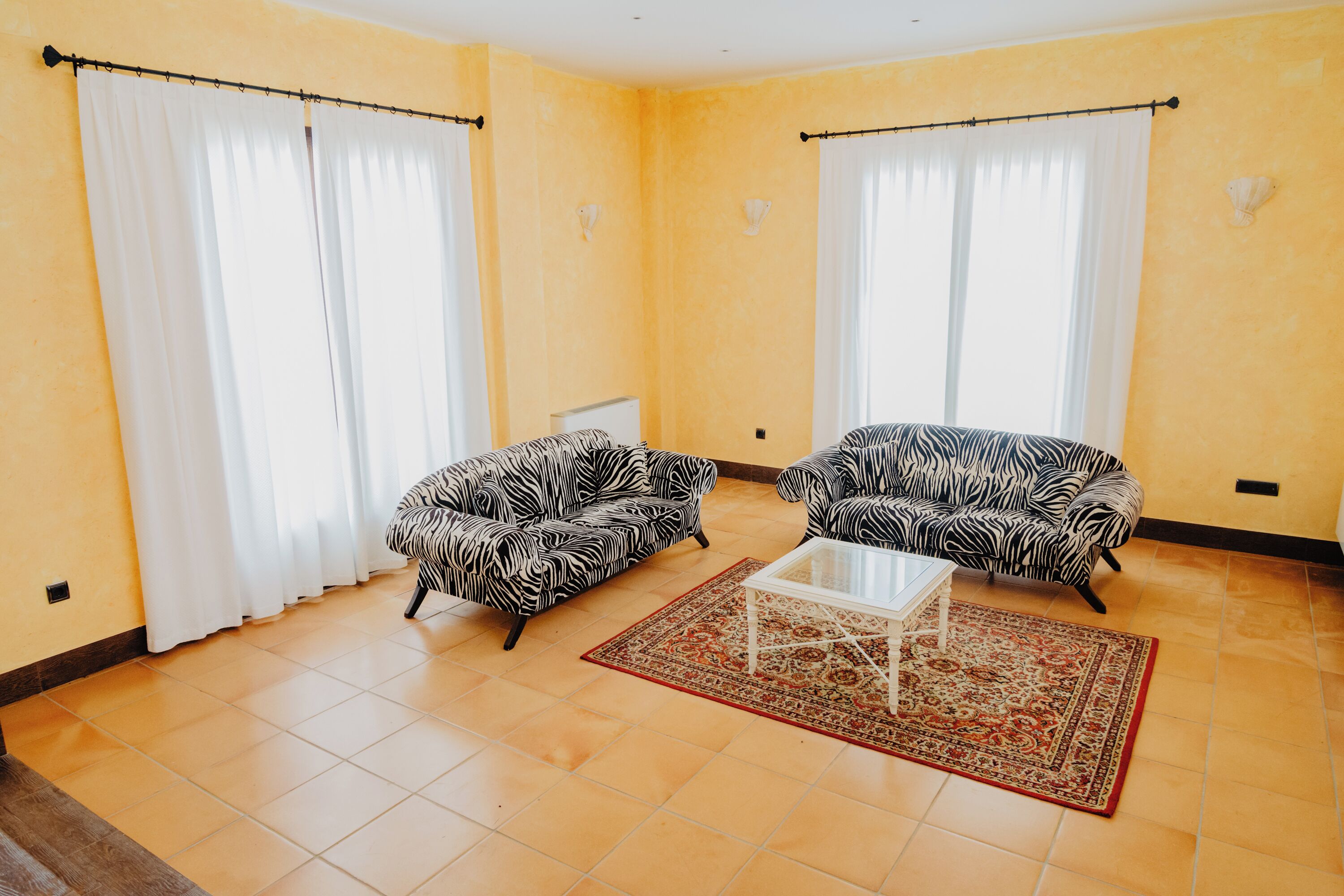 A living room with two zebra-patterned sofas, a coffee table, and a patterned rug.
