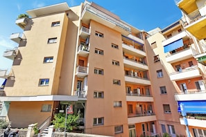 Un immeuble rĂ©sidentiel Ă plusieurs Ă©tages, dotĂ© de balcons, dâune entrĂ©e bien visible et dâune plaque de rue.