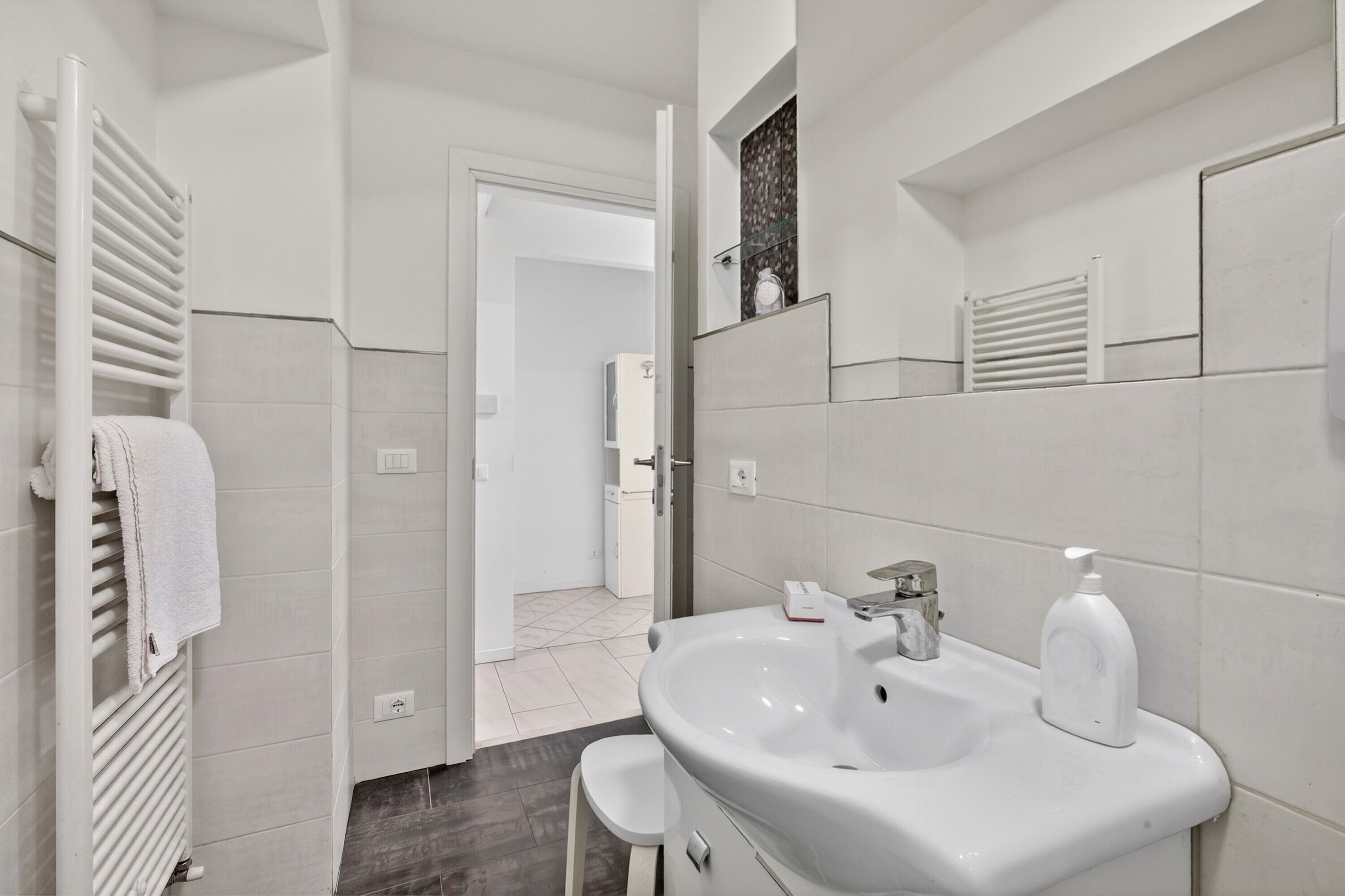 A modern bathroom with a white sink, a mirror, and a towel rack.